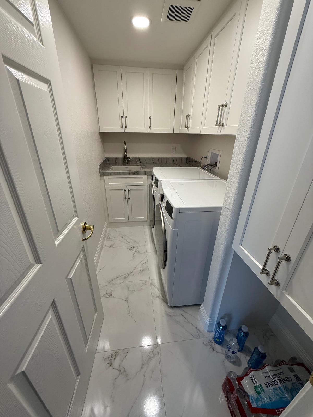 Laundry room with white shaker cabinets, marble-look countertop, and a utility sink.