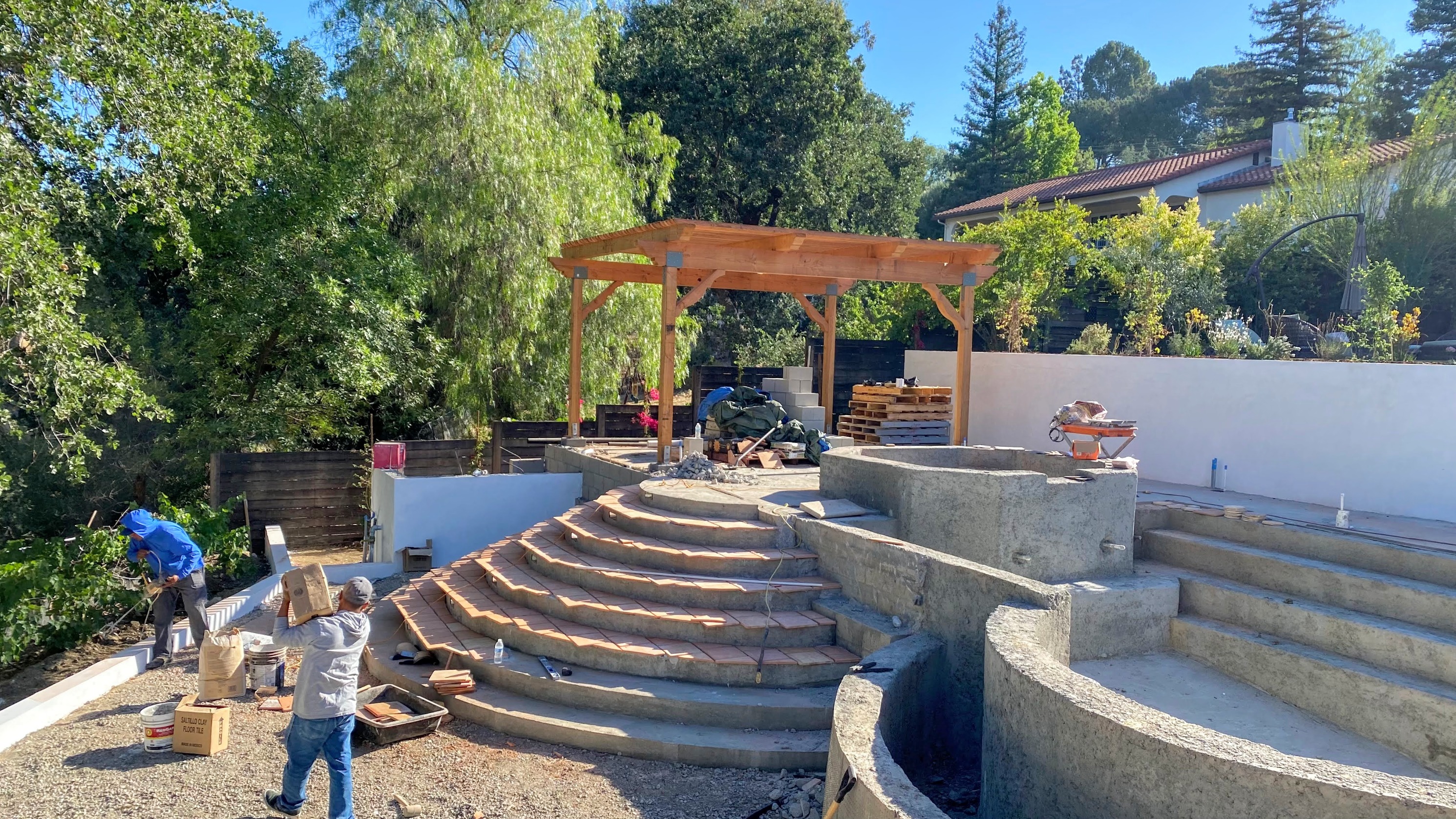 Transforming raw concrete into hand-crafted beauty — custom tile installation and pergola framing underway.